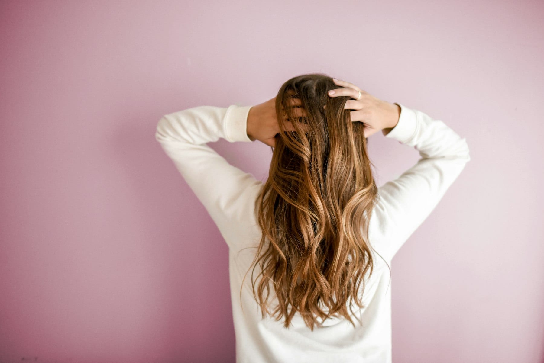 Healthy hair, photographed from behind against a muted wall